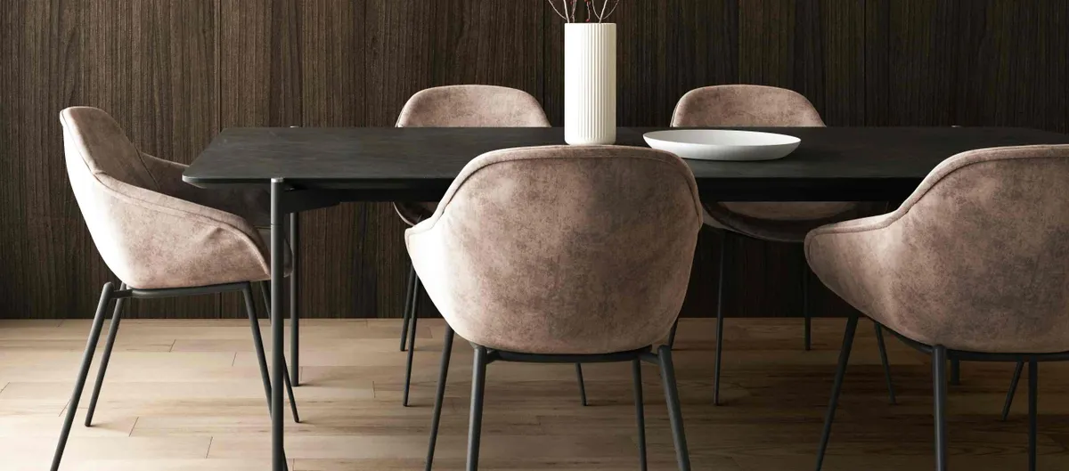 Eetkamerstoelen met roze-bruine bekleding om een zwarte tafel